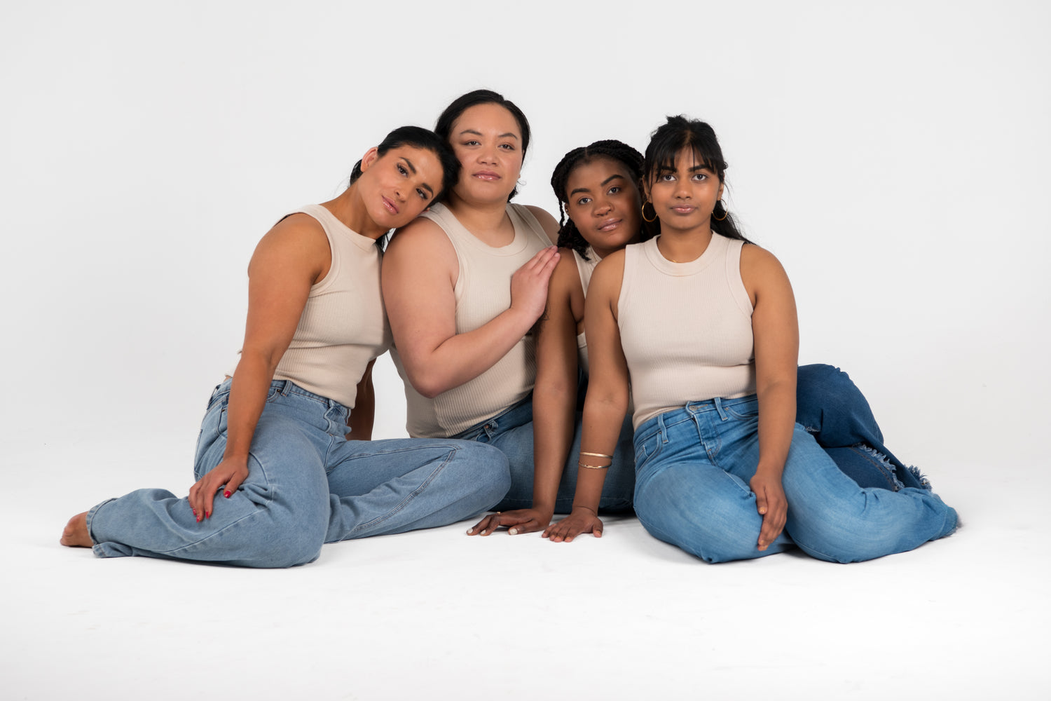 Four women sitting together on a white background