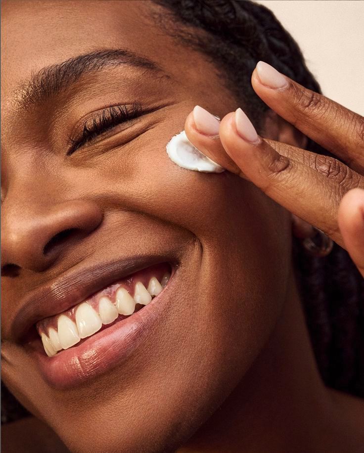 Woman applying the day cream cream to her face with a close-up focus on her hand and skin.