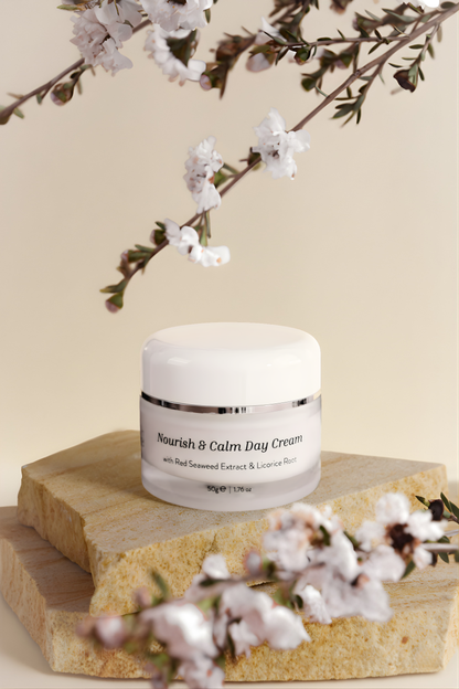 Jar of 'Nourish & Calm Day Cream' on a wooden block with cherry blossoms