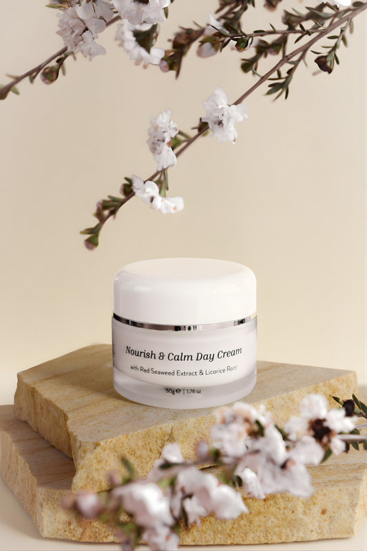 Jar of 'Nourish & Calm Day Cream' on a wooden block with cherry blossoms