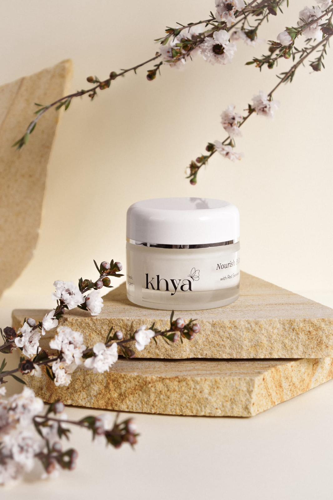 Khya skincare jar on a stone block with floral decorations