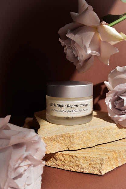 Jar of Rich Night Repair Cream with flowers on a stone surface