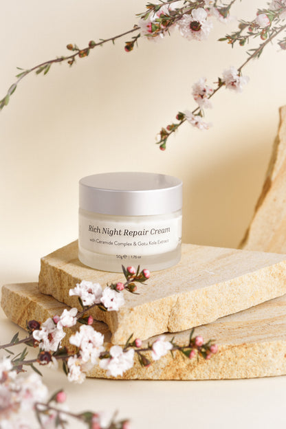 Jar of Rich Night Repair Cream on a wooden surface with cherry blossoms