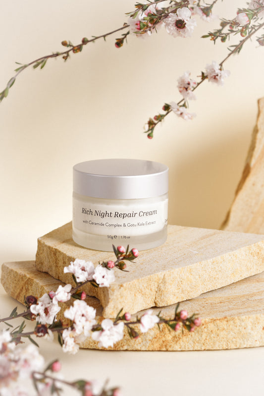 Jar of Rich Night Repair Cream on a wooden surface with cherry blossoms